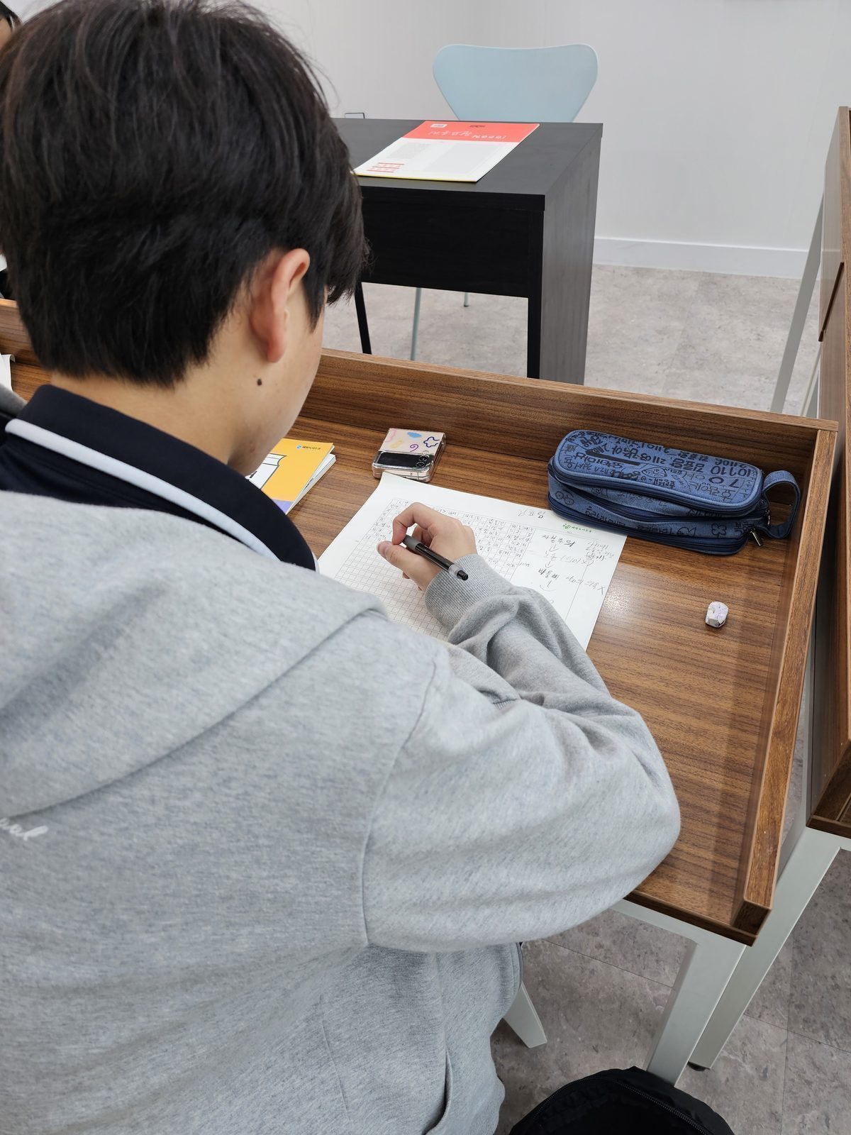 원목 열람석에서 원고지에 글을 쓰는 학생
