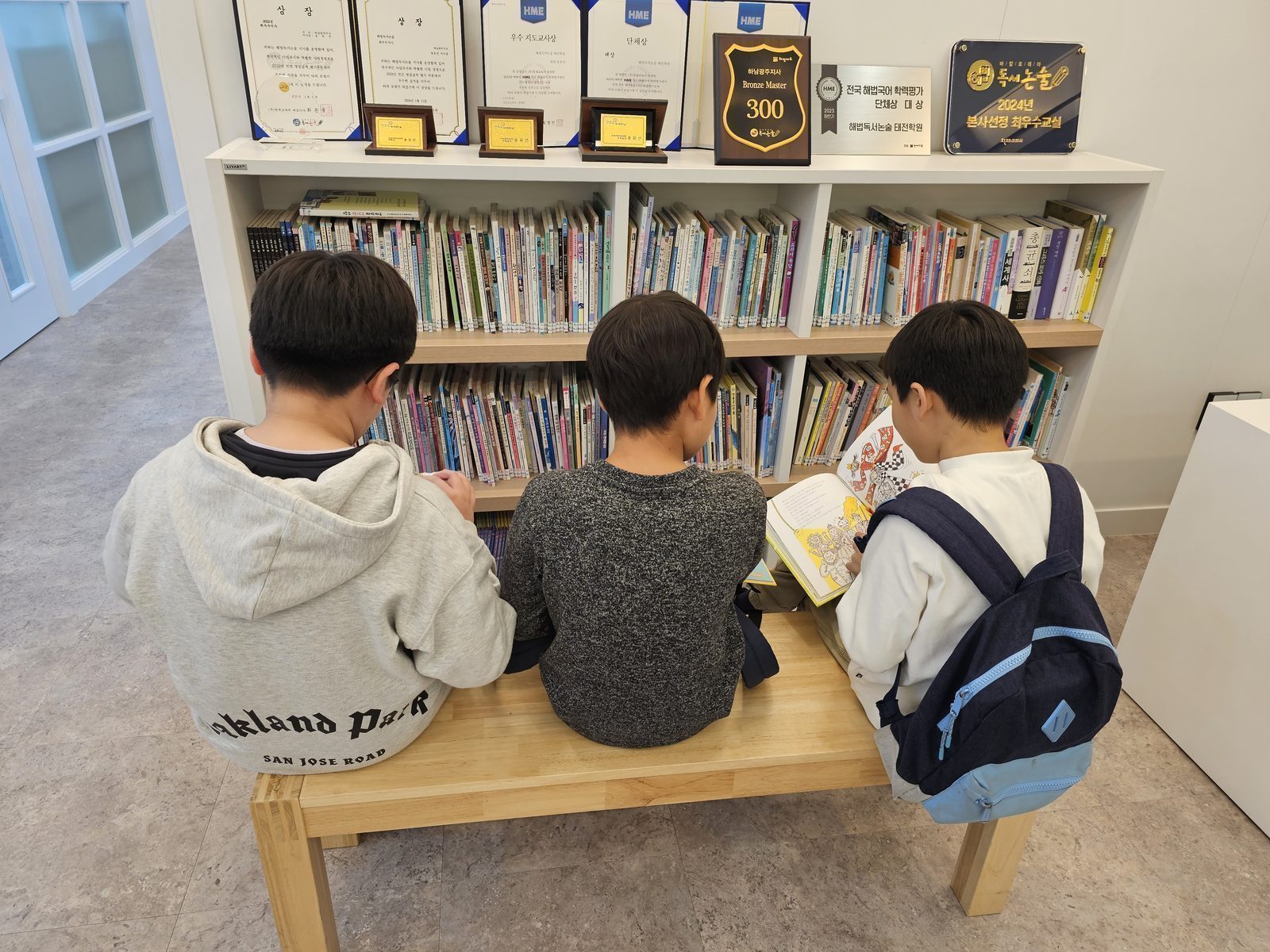 수상 진열과 서가 앞에서 책을 읽는 아이들